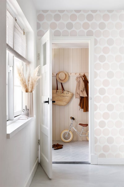 Heller Flur mit Mustertapete, offener Tür und dekorativen Elementen