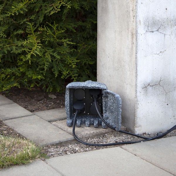 Steckdosensäule in Steinoptik für den Außenbereich mit zwei angeschlossenen Kabeln.