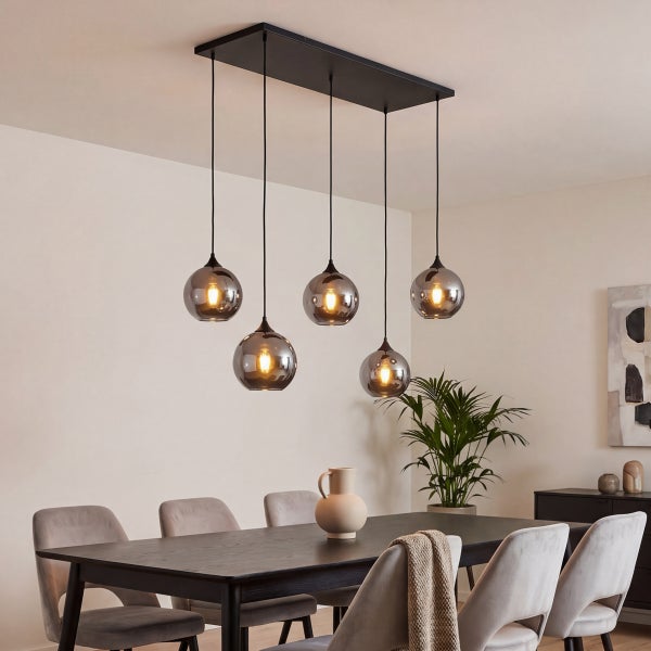 Fünfflammige Pendelleuchte mit rauchgrauen Glaskugeln über einem dunklen Esstisch in einem modern eingerichteten Esszimmer.