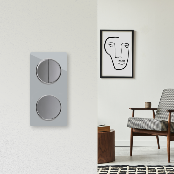 Doppelwippschalter an einer Wand neben einem modern eingerichteten Wohnbereich mit Sessel und abstraktem Bild