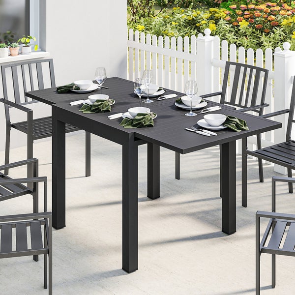 Moderne Garten-Essgruppe mit ausziehbarem Metalltisch und Armlehnstühlen auf einer Terrasse, gedeckt für sechs Personen neben einem Zaun.