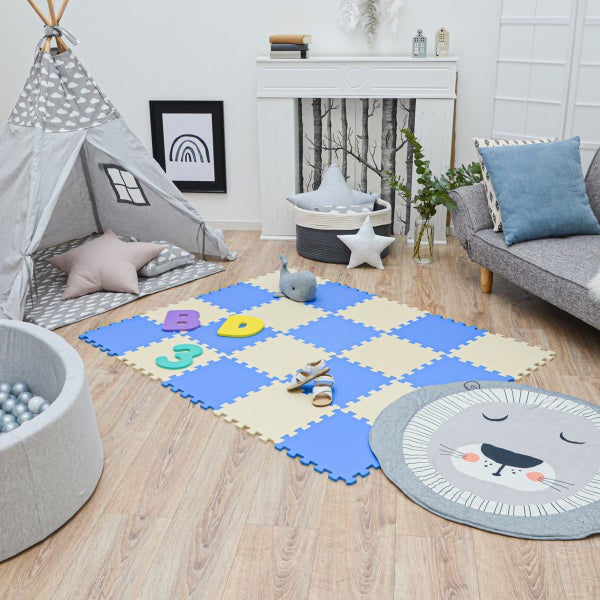 Hell eingerichtetes Kinderzimmer mit Tipi Zelt, Bällebad, blau beiger Spielmatte, Löwen Rundteppich und Sofa auf Holzboden.