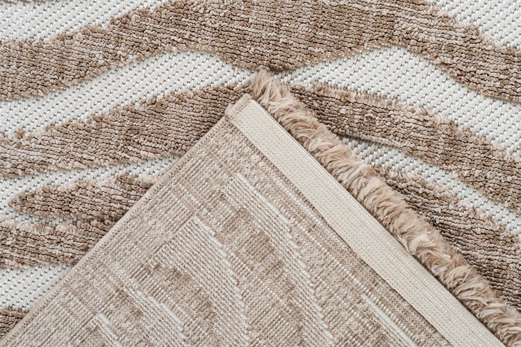 Nahaufnahme eines texturierten Teppichs mit wellenförmigem Muster und Hoch-Tief-Struktur, eine Ecke ist umgeschlagen und zeigt die Rückseite.