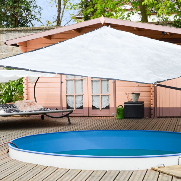 Weißes Sonnensegel gespannt über einer Holzterrasse mit rundem Pool und einem Gartenhaus.