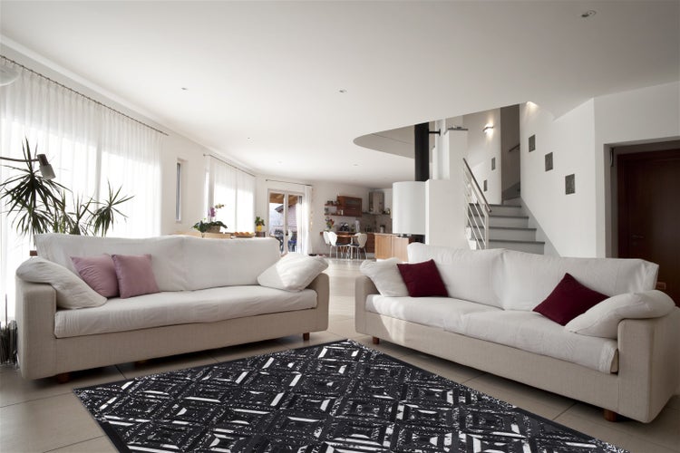 Geräumiges Wohnzimmer mit zwei Sofas und einem auffälligen Teppich mit geometrischem Muster auf einem hellen Boden in einem offenen Wohnbereich.