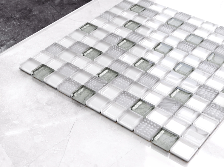 Glasmosaik mit quadratischen Steinen in Weiß und Grau mit verschiedenen Oberflächenstrukturen und Metallic-Effekt.