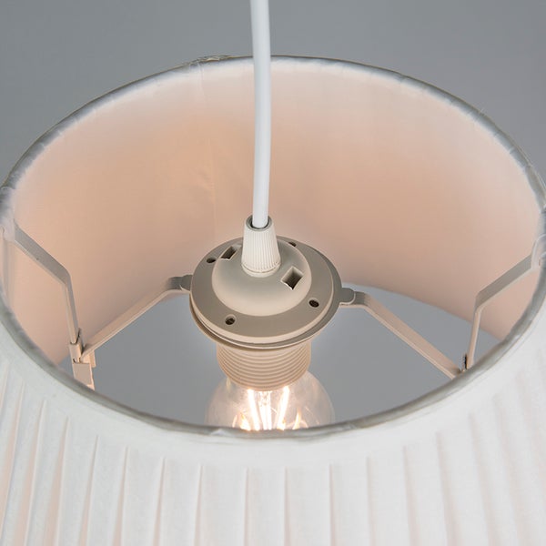 Nahaufnahme der Innenseite eines weißen, plissierten Lampenschirms mit Lampenfassung und Leuchtmittel.