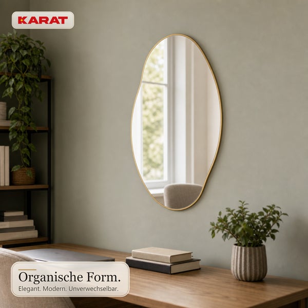 Wandspiegel mit organisch geformtem Rahmen an einer Wand über einem Schreibtisch mit Dekoration und Karat Logo.