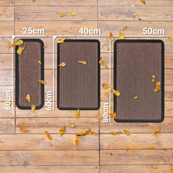 Drei Fußmatten in verschiedenen Größen liegen auf einem Holzboden.