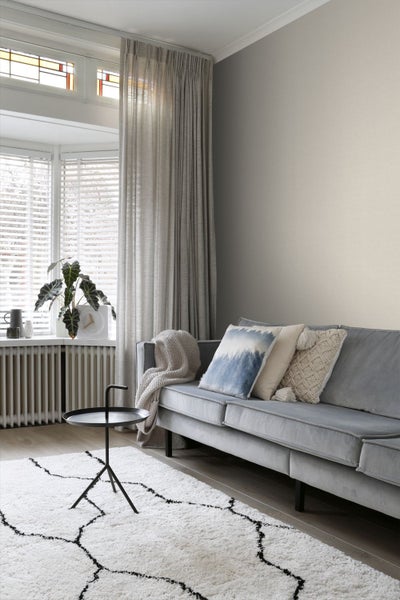 Wohnzimmer mit Sofa, Kissen, Vorhängen und Teppich