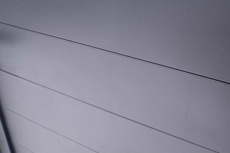 Detailaufnahme einer glatten, anthrazitfarbenen Oberfläche mit horizontalen Linien.