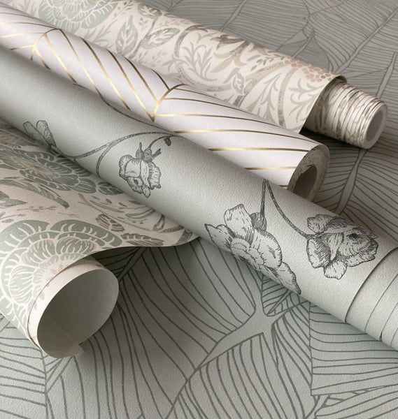 Verschiedene Tapetenrollen mit floralen Mustern, geometrischen Linien und Blattmotiven in hellen Farbtönen.