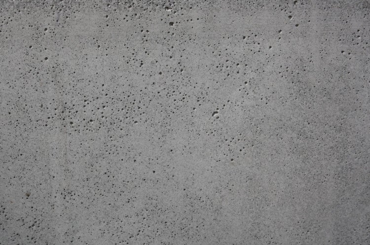Detailansicht einer grauen Betonoberfläche mit poröser Struktur.