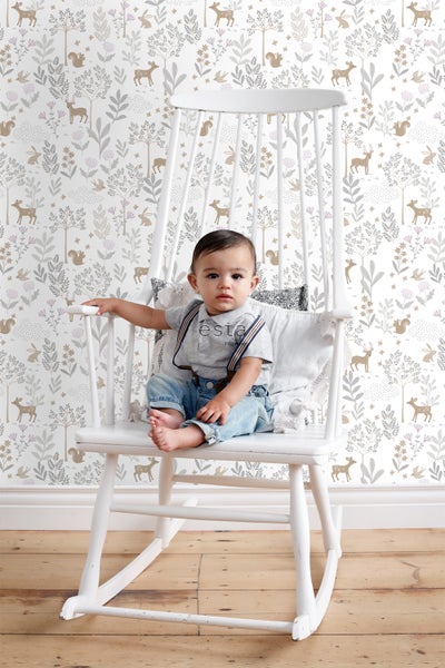 Ein Kind sitzt auf einem Schaukelstuhl vor einer Wand mit Tiermotiven.