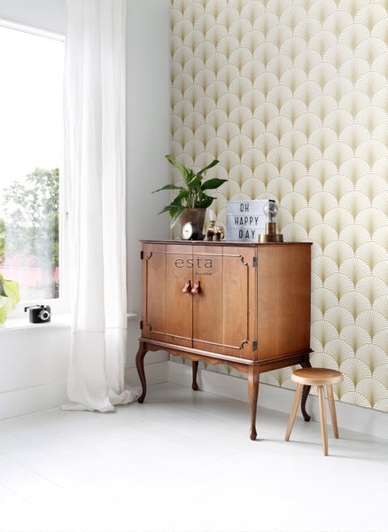 Wohnzimmer mit Tapete im Fächerdesign, Holzschrank und Hocker.