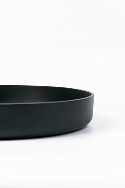 Rundes, schwarzes Aufsatzwaschbecken aus Keramik mit matter Oberfläche.