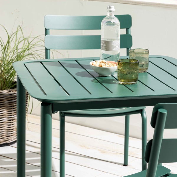Moderner Gartentisch aus grünem Metall mit Lattenoberfläche und passenden Stühlen auf einer Holzterrasse.