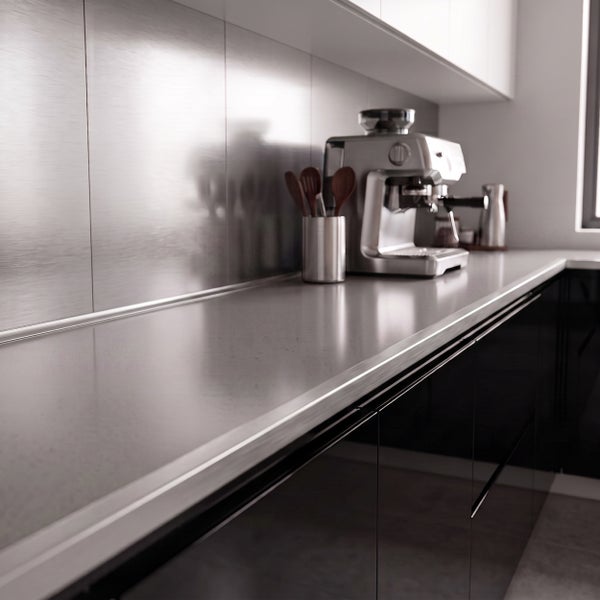 Moderne Küche mit glatter Küchenarbeitsplatte, Edelstahl Nischenrückwand und einer Espressomaschine auf der Anrichte.