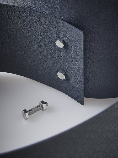 Detailaufnahme von Sechskantschrauben und Muttern an einem dunklen Bauteil mit Oberflächenstruktur.