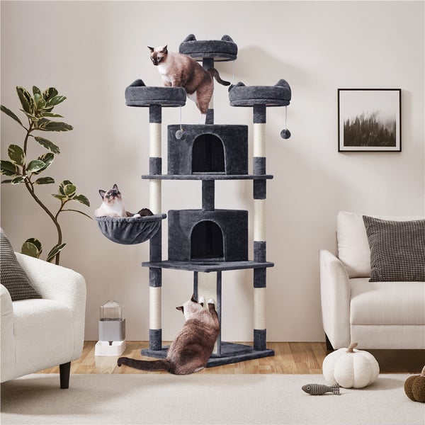 Grauer Katzenkratzbaum mit mehreren Ebenen, Höhlen und Liegeflächen in einem hellen Wohnzimmer mit drei Katzen.