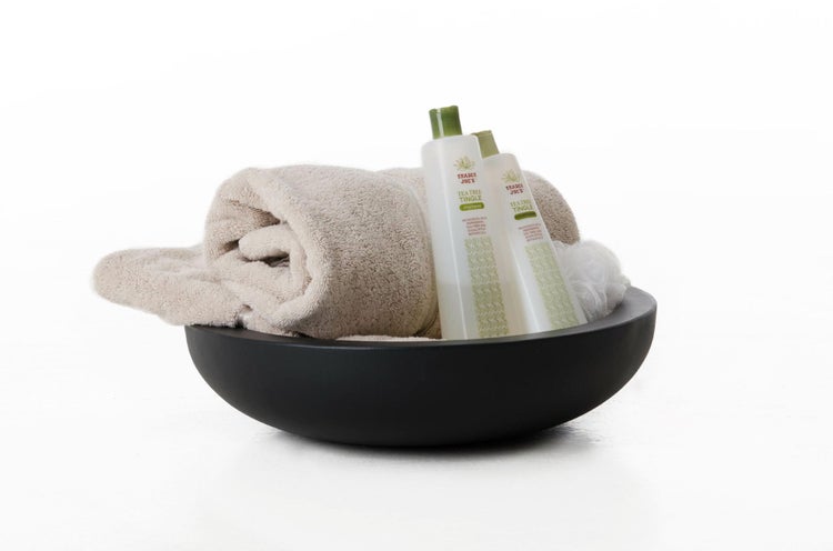 Aufsatzwaschbecken mit einem zusammengerollten Handtuch, Shampooflaschen und einem Duschschwamm.