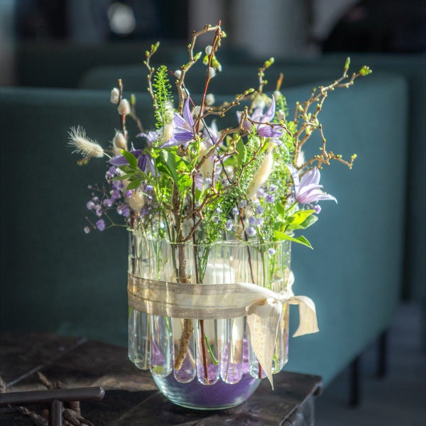 Blumenstrauß in einer Glasvase aus Reagenzgläsern mit dekorativem Band verziert