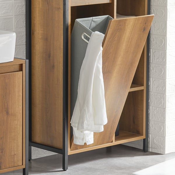 Offener Wäschekorb in einem Badezimmerregal mit Holzeffekt und schwarzem Metallrahmen, ein weißes Hemd hängt heraus.