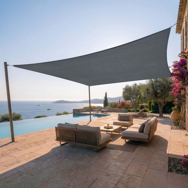 Großes rechteckiges Sonnensegel über einer hellen Terrasse mit modernen Gartenmöbeln, Pool und Blick auf das Meer.