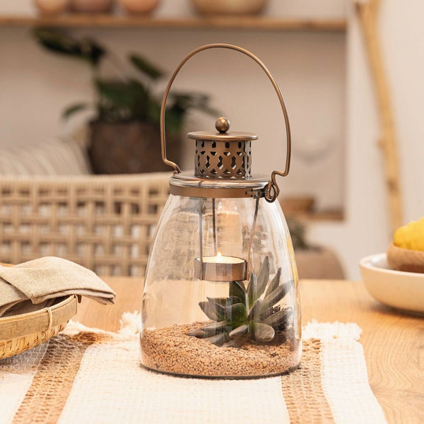Dekorative Glaslaterne mit Pflanze und Teelicht auf einem Tisch
