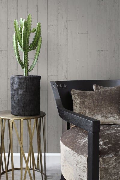 Dekoratives Interieur mit Kaktus in einem Topf auf einem Beistelltisch, einem Sessel und einer Wand mit Holzpaneel-Tapete.