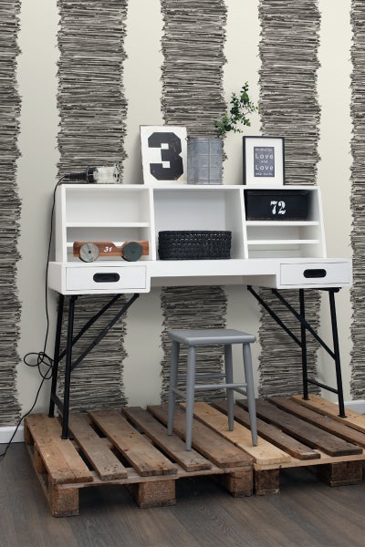 Weißer Schreibtisch mit Ablagefächern und Hocker auf Holzpaletten vor gestreifter Tapete