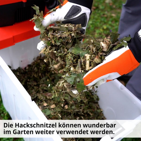 Gartenhäcksler in Verwendung mit Gartenhandschuhen beim Einfüllen von Häckselgut in einen Behälter.