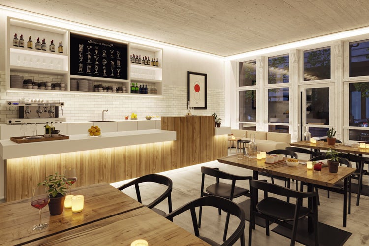 Modernes, helles Cafe-Interieur mit Holztischen, schwarzen Stühlen, einer beleuchteten Holztheke und weißen Fliesen an der Rückwand.