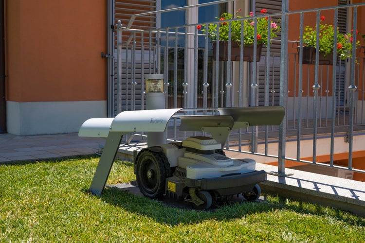 Rasenmäherroboter auf Rasen vor Hauswand und Balkon