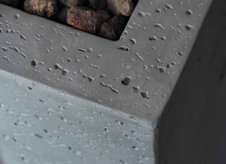 Detailansicht einer grauen Feuerschale aus Beton mit Lavasteinen.