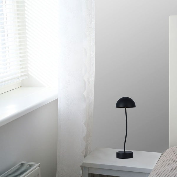 Schlafzimmer mit Nachttisch und darauf stehender Tischleuchte