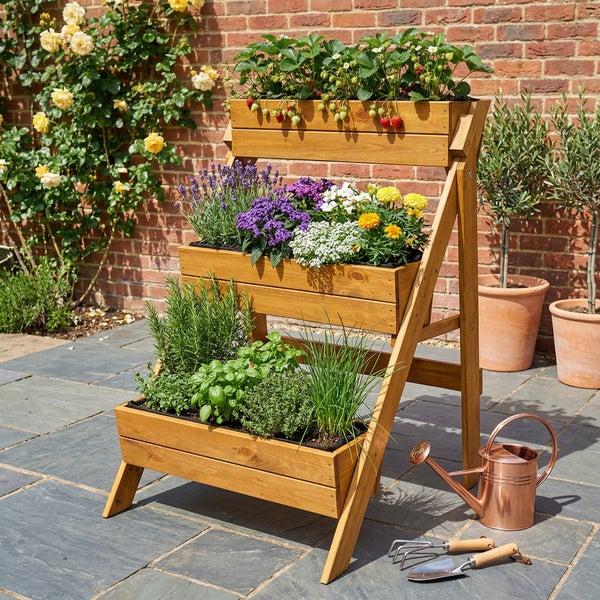 Dreistufiges Pflanzregal aus Holz in Leiterform auf einer Terrasse mit Erdbeeren, Blumen und Kräutern sowie Gießkanne und Gartenwerkzeug.