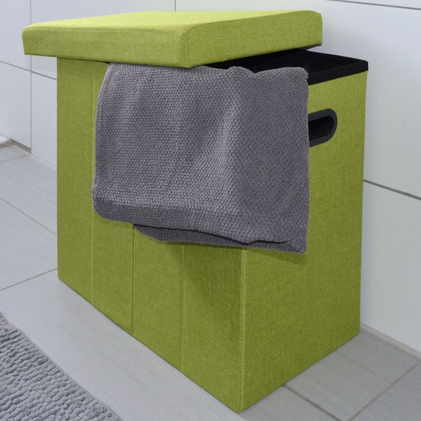 Grüner faltbarer Wäschehocker mit Deckel und Tragegriff aus Stoff, in einem Badezimmer mit grauem Handtuch über dem Rand.