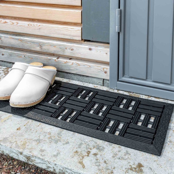 Schmutzfangmatte aus Gummi vor einer Haustür mit Schuhen