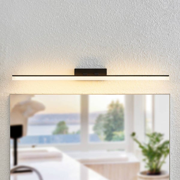 Lineare, schwarze LED-Spiegelleuchte montiert über einem Badezimmerspiegel in einer hellen Umgebung.