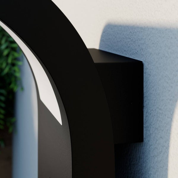 Detailansicht einer schwarzen Wandleuchte mit gebogenem Profil und integrierter LED Beleuchtung montiert an einer Wand.