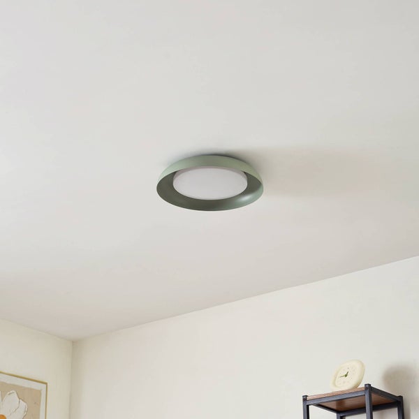 Runde grüne Deckenleuchte mit weißem Diffusor in flachem Design an einer weißen Zimmerdecke.
