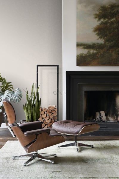 Wohnzimmer mit Sessel und Ottomane aus Holz und Leder, Kamin und Kunstwerk.