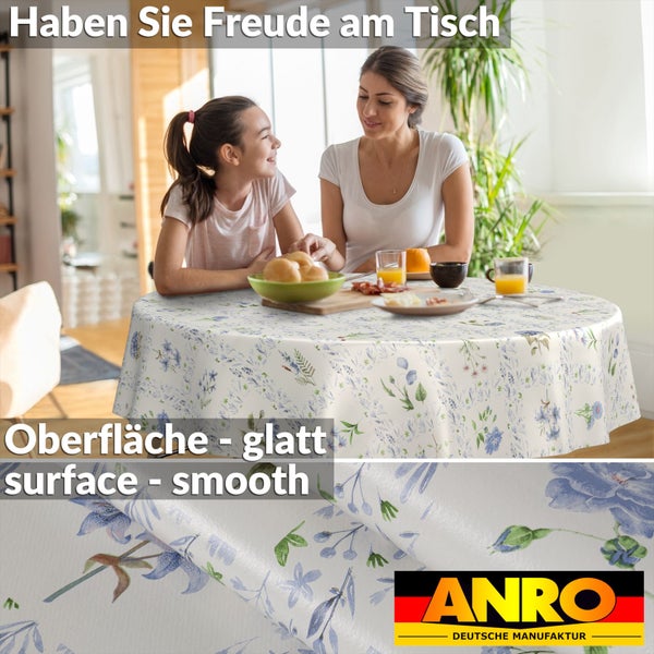 Runde Wachstuch-Tischdecke mit Wiesenblumen-Muster auf einem gedeckten Tisch. Detailansicht der glatten Oberfläche. ANRO Logo.