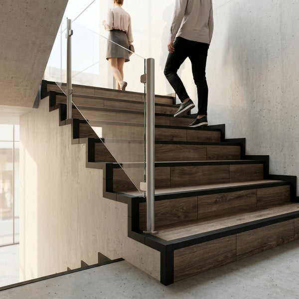Moderne Treppe mit dunklen Stufen in Holzoptik, schwarzer Metallkonstruktion und Glasgeländer an Betonwänden.