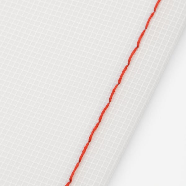 Detailaufnahme einer weißen Baufolie mit Gitterstruktur und einer roten Naht.
