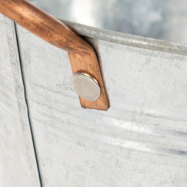 Detailaufnahme eines verzinkten Metalleimers mit einem kupferfarbenen Griff und einer stabilen Nietverbindung.