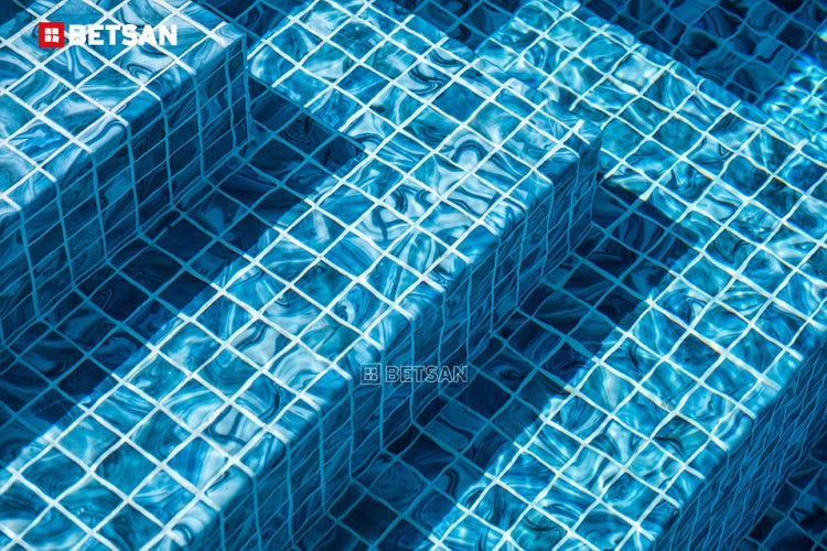 Nahaufnahme von Poolstufen mit blauem Mosaik und Betsan Logo