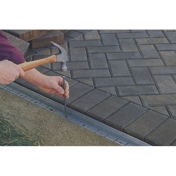 Montage einer Pflasterkante mit Hammer und Erdnagel an einer gepflasterten Fläche aus Steinen.