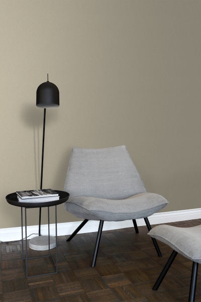 Wohnzimmer mit Sessel, Stehlampe und kleinem Tisch vor einer strukturierten Wand.